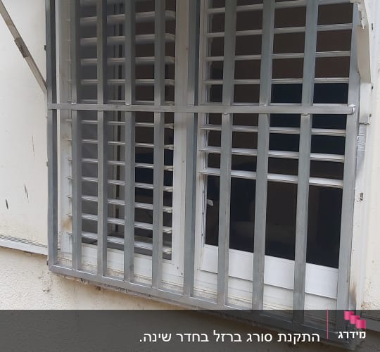 סורגים מתכתיים על חלון עם תריסים לבנים